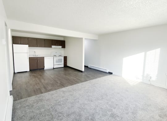 Open living room looking into dining area and galley kitchen with wall dividing hallway. White appliances, cabinet storage.at Laurel Park, Twin Falls, 83301