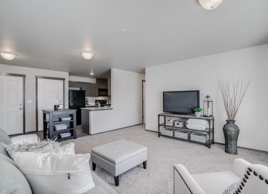 Large carpeted living showing a chair, couch, tv and plant. Open floor plan from dining room and kitchen. Hallway off of living to bedrooms. at Altitude, East Wenatchee, WA