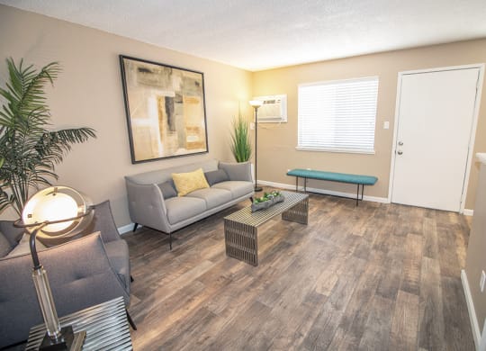 Living room with large window, staged with couch, chair, two tables, lamps and plants at Woodland Village , California, 95695