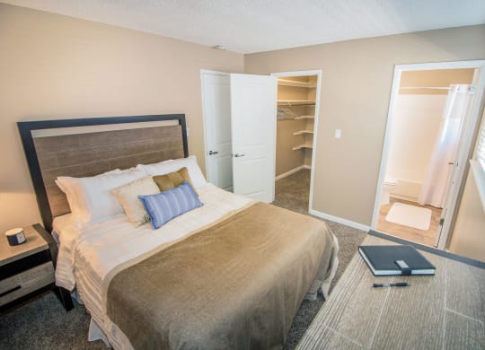 Bedroom with large closet and custom shelving to left and bathroom to right. Staged with bed and dresser at Woodland Village , Woodland, 95695