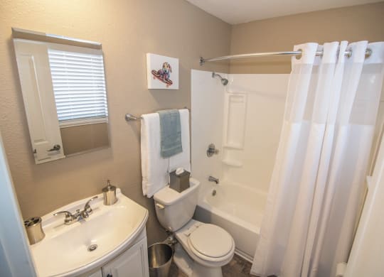 Master Bathroom with white fixtures, large bathtub and window at Woodland Village Apartments , Woodland California