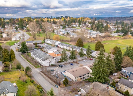 Aerial view of the community with trees along the skyline, houses, and large grass fields in the surrounding area.at The Trail, Snohomish, WA