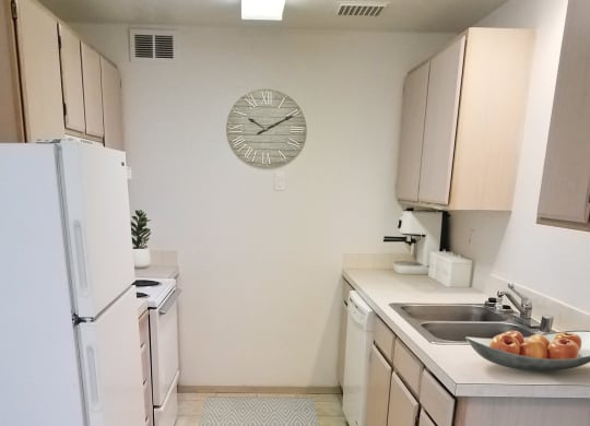 Double galley kitchen with top and bottom cabinets, full fridge, oven and stove top on left side, dishwasher, sink on right.at North Pointe, Post Falls, 83854