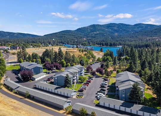 View of The Overlook Apartments in Post Falls, Idaho with mature trees, and mountains in the distance.