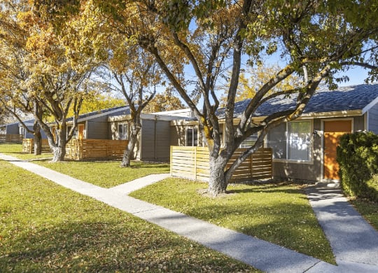 Sidewalks outside units with fenced yards with large trees and grassy areas at Park View Apartments, Washington