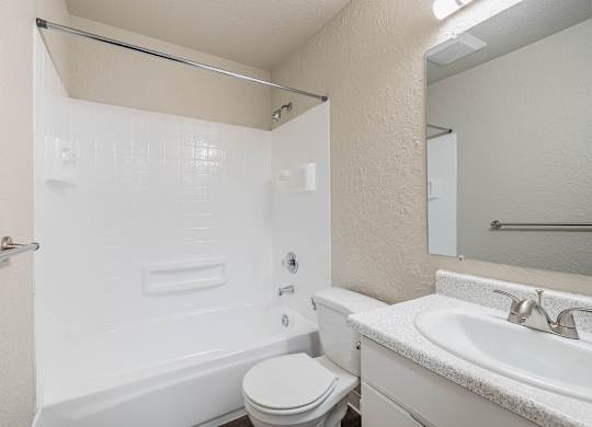 Clean bathroom with a standard toilet, sink, and white finishes in a Peak 88 Apartment home in Renton, WA.