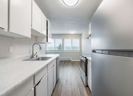 Updated kitchen with white cabinetry and a stainless-steel refrigerator in a Peak 88 Apartment home in Renton, WA.