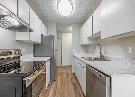 Kitchen with white cabinets, stainless-steel dishwasher, and bright natural light in a Peak 88 apartment in Renton, WA.