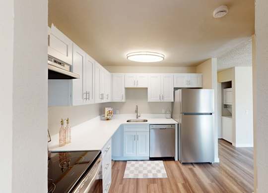 Contemporary kitchen at Peak 88 Apartments Renton WA with sleek white cabinets, stainless appliances, and wood-style floors.
