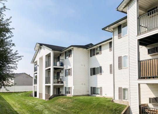 a view of apartments with balconies surrounded by green grass. at North Pointe, Post Falls, ID 83854