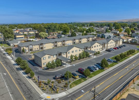 an aerial view of an apartment complex with cars parked on the street