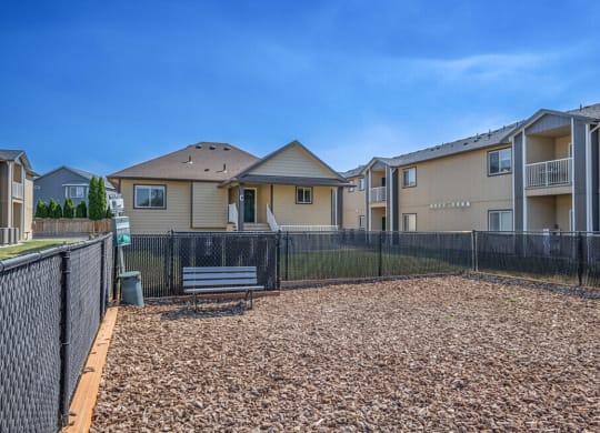 a fenced in area with a bench in front of apartment buildings
