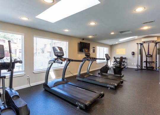 two treadmills and other exercise equipment in the gym of a home