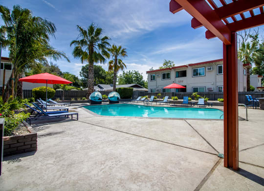 Resort style pool with lounge chairs, umbrellas, covered seating and BBQ at Woodland Village Apartments , California, 95695