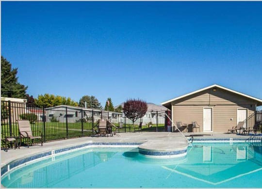 Swimming pool and pool house with lounge chairs and trees in the distance at Park View Apartments, Wenatchee Washington