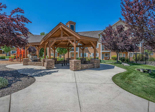 A large wooden building with a porch and a stone wall in front.