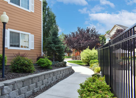 Walkway through apartment community in West Richland, WA surrounded by green plants.