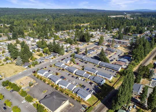 Exterior community ariel view, property is lined with trees, grass, and mountain tops in the background.at Quilceda Gardens, Washington, 98270