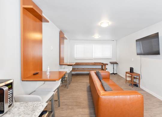 A modern resident lounge with a long orange sofa and a television on the wall at our Billings apartments in MT.