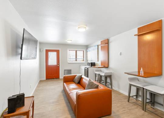 A living room with a couch, a television, and a bar area at Rock Creek Apartments in Billings, MT.