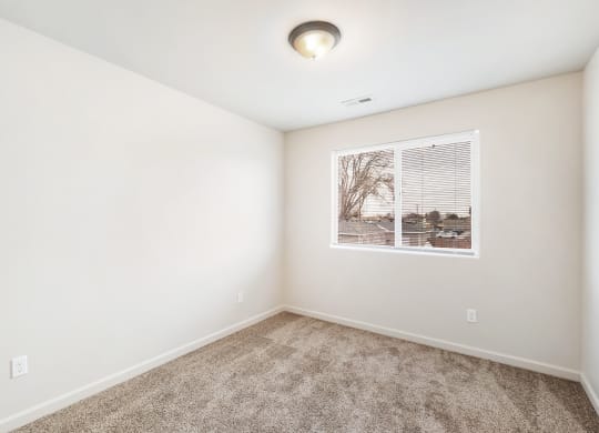 Clean, bright bedroom with taupe carpet, white walls and a large window on one wall. at Pine Tree Park, Washington