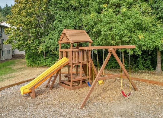 a wooden swing set with a yellow slide in a backyard  at Sitka Heights, Washington, 98424