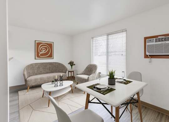A dining room with a white table and chairs that opens to a living room at our Billings Apartments in Montana.