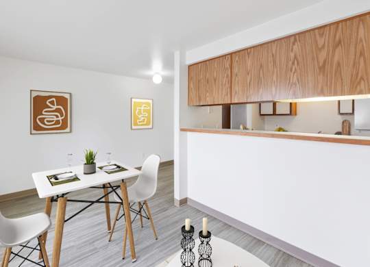 A dining area with a white table and chairs with a kitchen to the right at Shiloh Glen Apartments in Billings, MT.