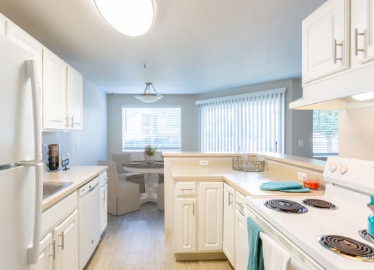 a kitchen with white cabinets and appliances and a dining room with a table