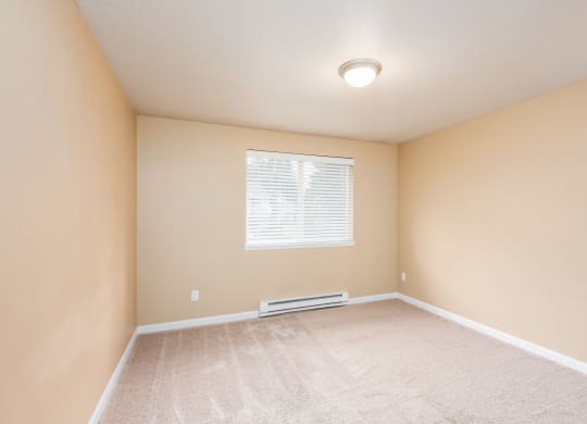 an empty room with beige walls and a window