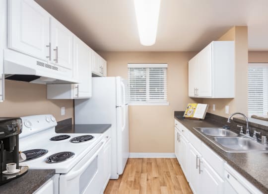 a kitchen with white appliances and counters and a sink