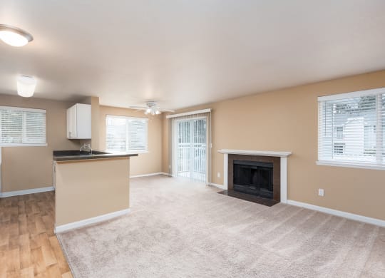 an empty living room with a fireplace and a kitchen