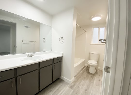 Spacious full bathroom with counter space, ample cabinet storage, sink, towel racks, shower, toilet, and frosted glass window.at Summit, Pocatello, ID
