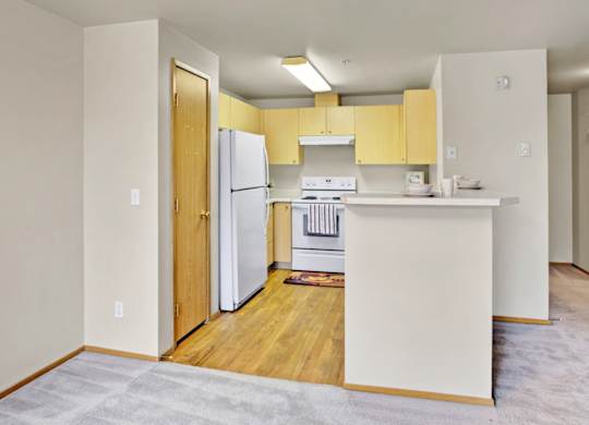 A kitchen with white appliances and yellow cabinets.