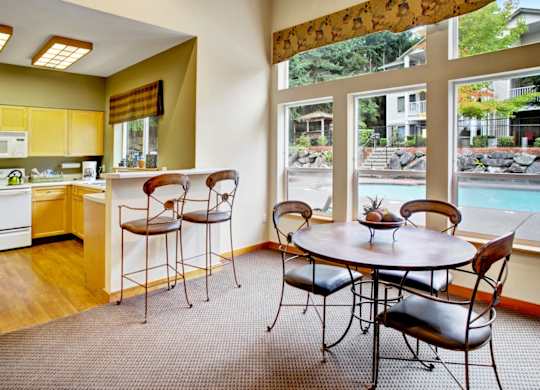 A kitchen with a table and chairs in front of a window.