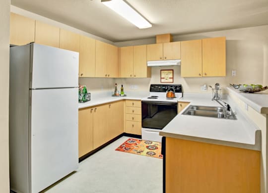 A kitchen with a white refrigerator and wooden cabinets.