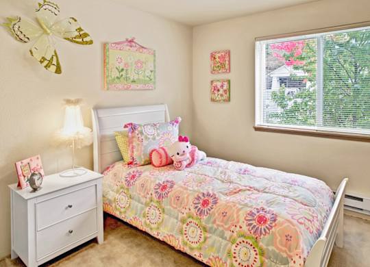 A bedroom with a bed, nightstand, and pictures on the wall.