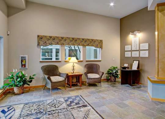 A waiting room with a rug and chairs.