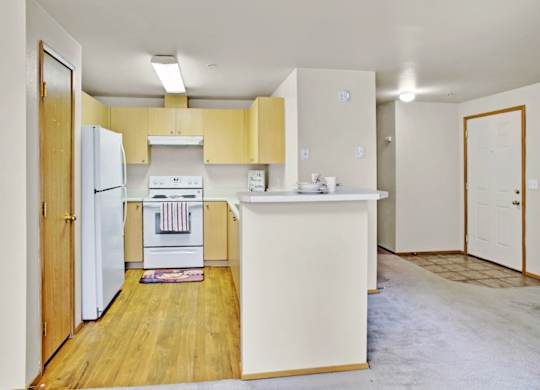 A kitchen with a white refrigerator and yellow cabinets.