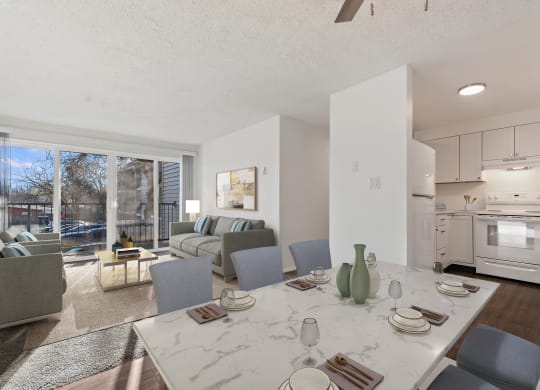 a living room with a table and chairs and a kitchen with a sliding glass door