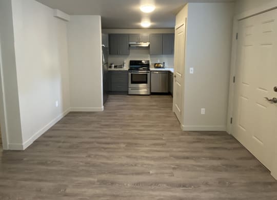 a view of a kitchen and a hallway with wood flooring at The Lakes in Moses Lake, WA.