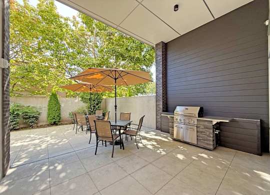 A patio with a table and chairs and an umbrella at The Duo Apartments in University Place, WA.