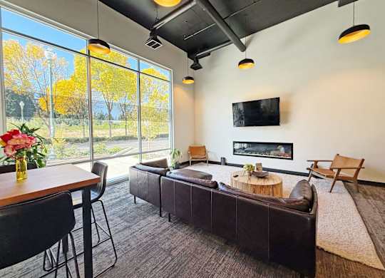 A modern living room with a flat screen TV mounted on the wall at The Duo Apartments in University Place, WA.