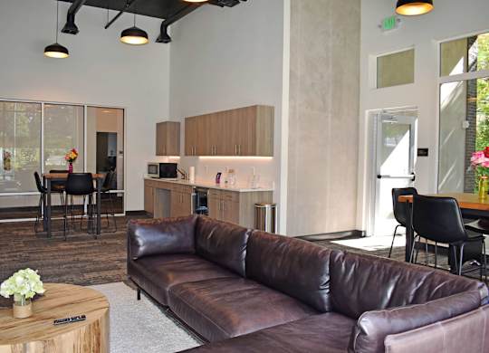 A brown leather couch in a room with a table and chairs at the Duo Apartments in University Place.