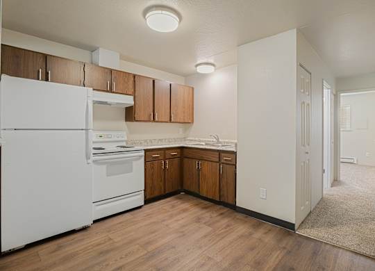Bright apartment kitchen with white appliances and wood cabinets at The Lakes Apartments in Moses Lake WA