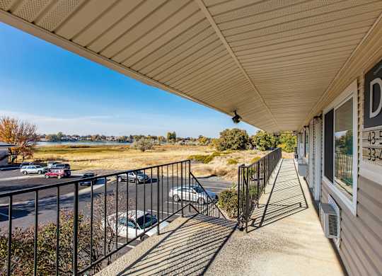 the front porch of a house with a balcony and a view of a parking lot