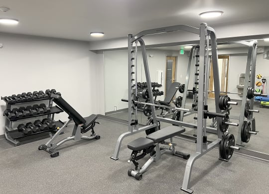 Fitness center with weight rack, free weights, squat, bench press rack, and two benches at University Glen, University Place, Washington