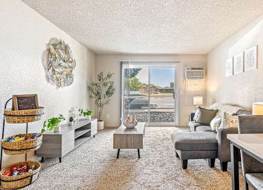 A living room with a grey couch and a white wall t Wildflower Apartments in Kennewick, WA.