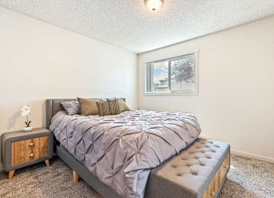 A bedroom with a bed, nightstand, and window at Wildflower, Kennewick, WA 99336.