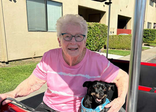 An elderly woman is sitting in a red car at Lodi Commons Senior Living, Lodi, CA